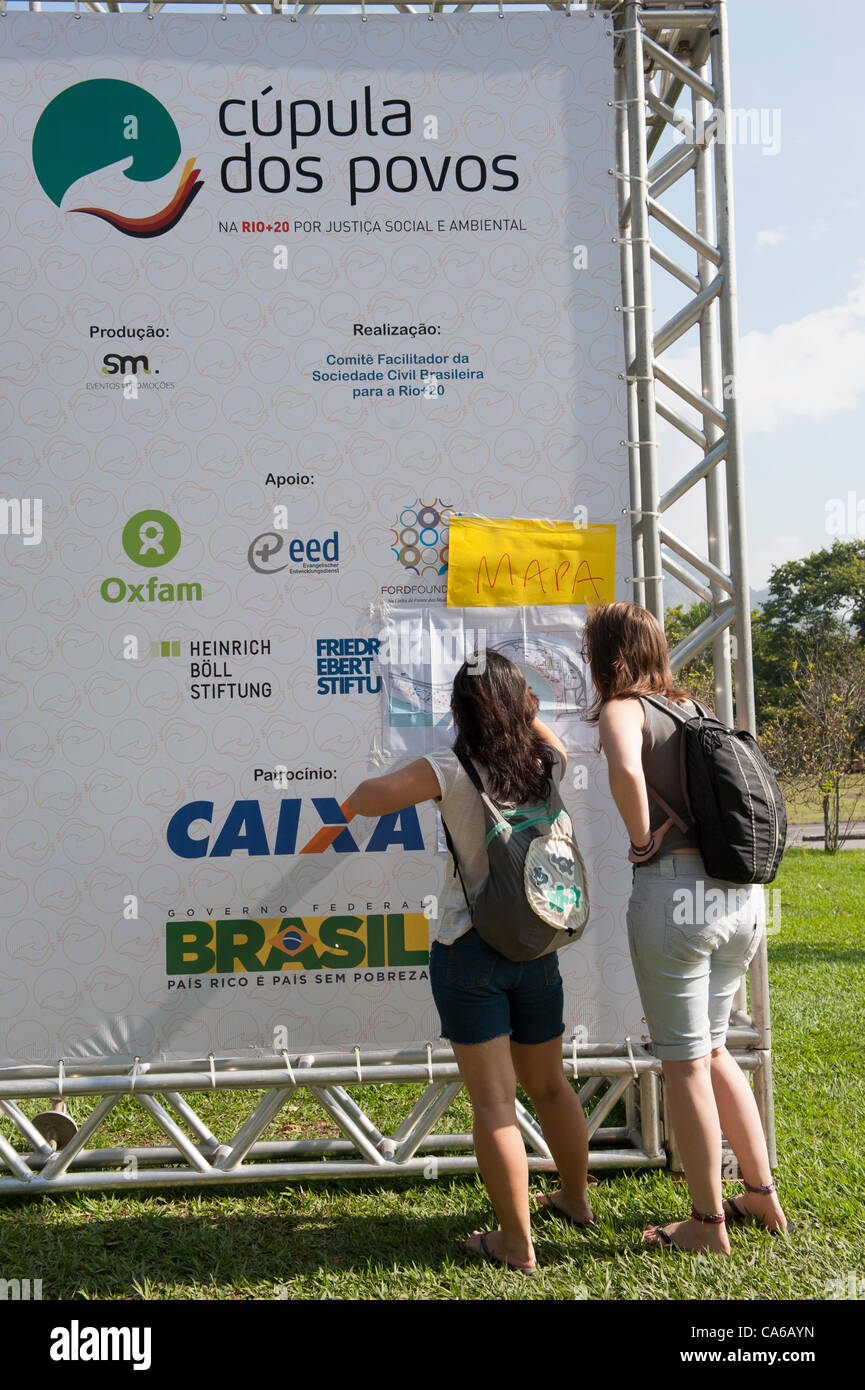 Dos visitantes intenta encontrar su camino alrededor de la Cumbre popular sitio con la ayuda de un mapa pegado a una cúpula dos Povos banner. Conferencia de las Naciones Unidas sobre Desarrollo Sostenible (Río+20), Río de Janeiro, Brasil, 15 de junio de 2012. Foto © Sue Cunningham. Foto de stock