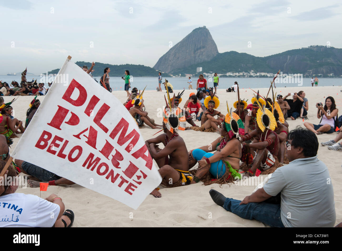Los pueblos indígenas y otros están comenzando a montar los derechos de banner en la playa de Flamengo con el Pan de Azucar en el fondo, para protestar contra la construcción de represas hidroeléctricas en los ríos de Brasil. Un participante lleva una bandera, 'Dilma Belo Monte Tcap' - 'Dilma [el presidente de Brasil] Deje de Belo Monte". La Cumbre de los pueblos en la Conferencia de las Naciones Unidas sobre Desarrollo Sostenible (Río+20), Río de Janeiro, Brasil, 19 de junio de 2012. Foto © Sue Cunningham. Foto de stock