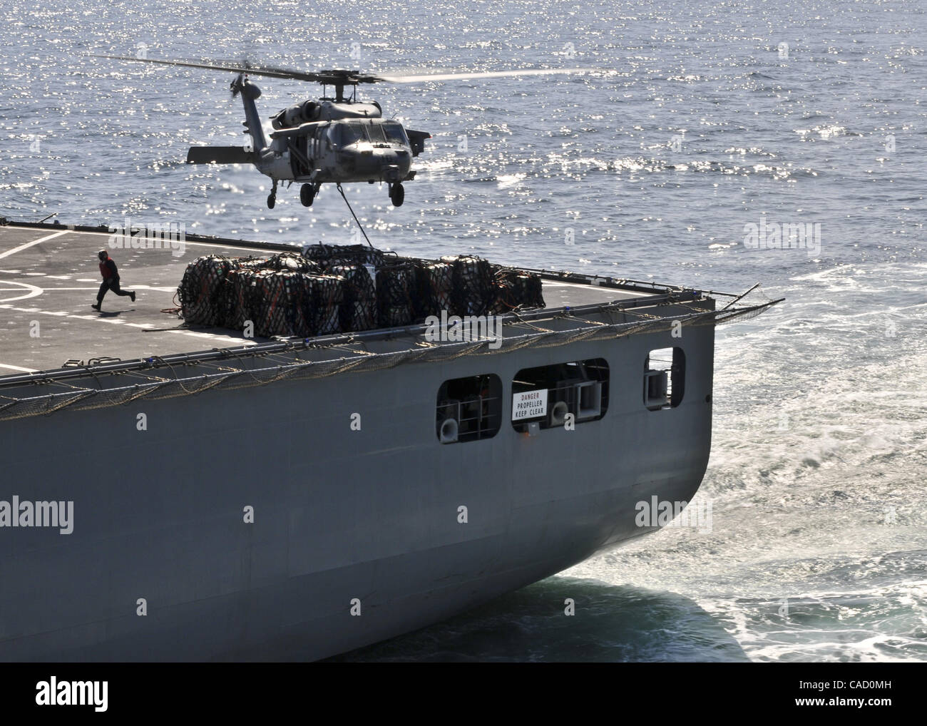 Junio 21, 2010 - Japón - Océano Pacífico (3 de abril de 2011) - Un MH-60S Sea Hawk helicóptero asignado al escuadrón de helicópteros de combate de mar 25 recoge los suministros desde el transporte marítimo de carga seca, comando militar/municiones buque USNS Matthew Perry (T-AKE 9) durante un reabastecimiento vertical con el asalto anfibio s Foto de stock