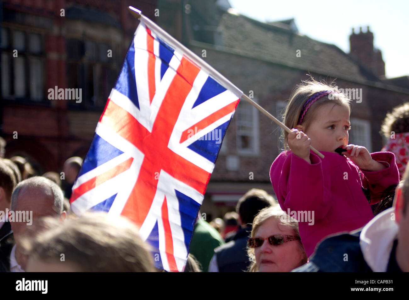 Joven vuela la Union Jack sobre una multitud de gente todos disfrazados de un vistazo de la Reina de Inglaterra como ella atiende de York Minster para servicio Santo, 5 de abril de 2012. York, Reino Unido. Foto de stock