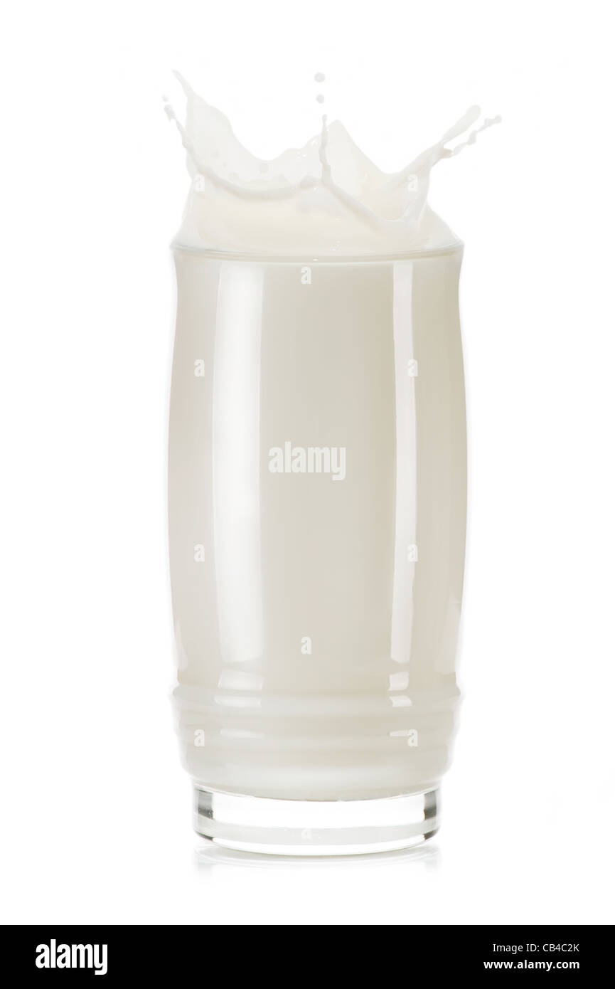 Vaso de leche con salpicaduras y gotas sobre fondo blanco. Foto de stock