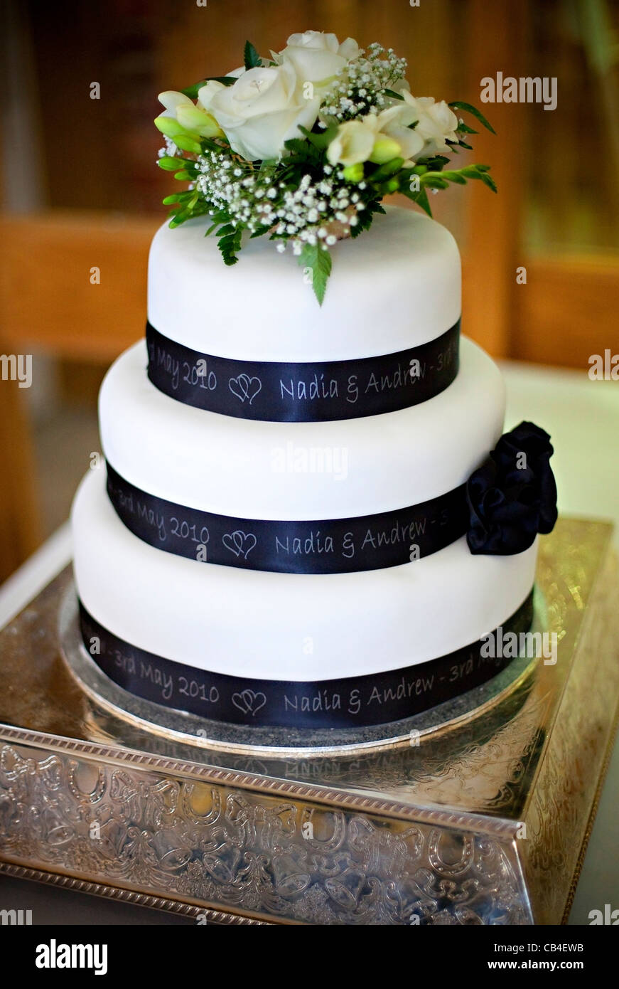 Tres niveles de pastel de bodas blanco con negro, cintas y flores en la  parte superior Fotografía de stock - Alamy