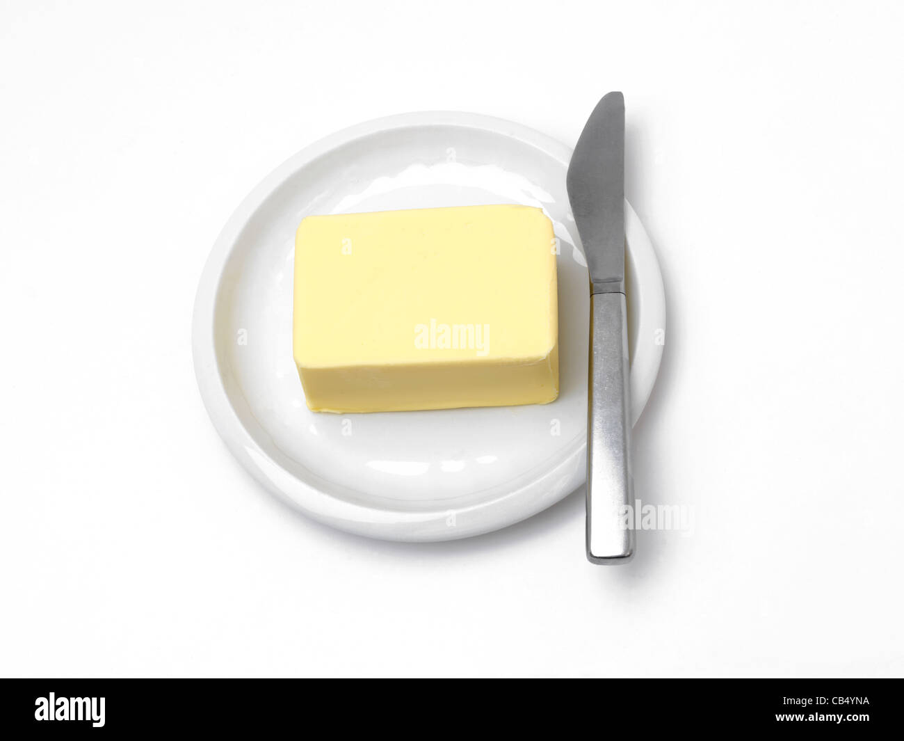 Bloque de mantequilla en un plato con un cuchillo por el lateral Foto de stock