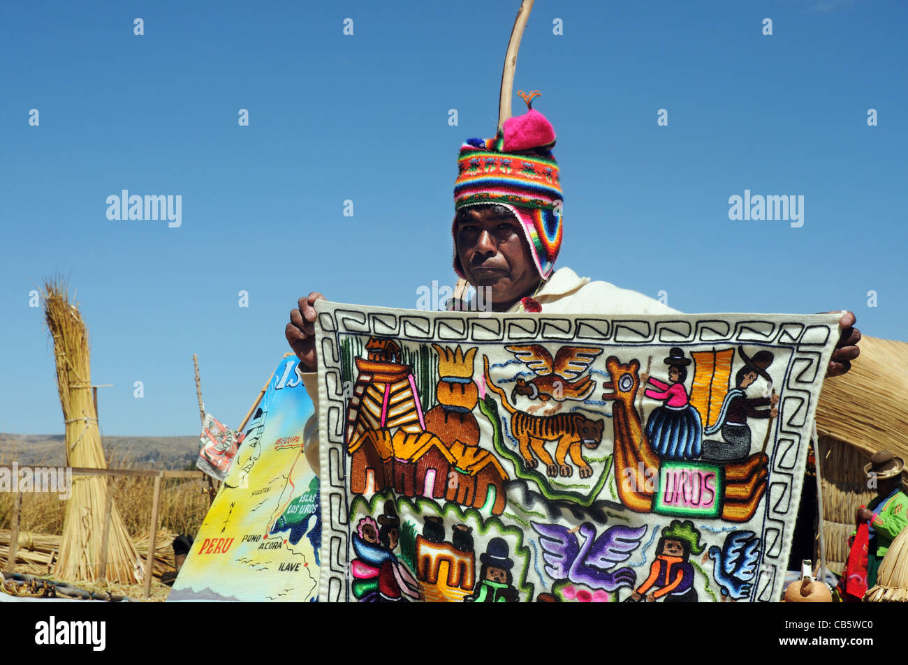 Un uros islander vendiendo un tapiz fabricado localmente, las Islas de los Uros, Lago Titicaca, Perú Foto de stock