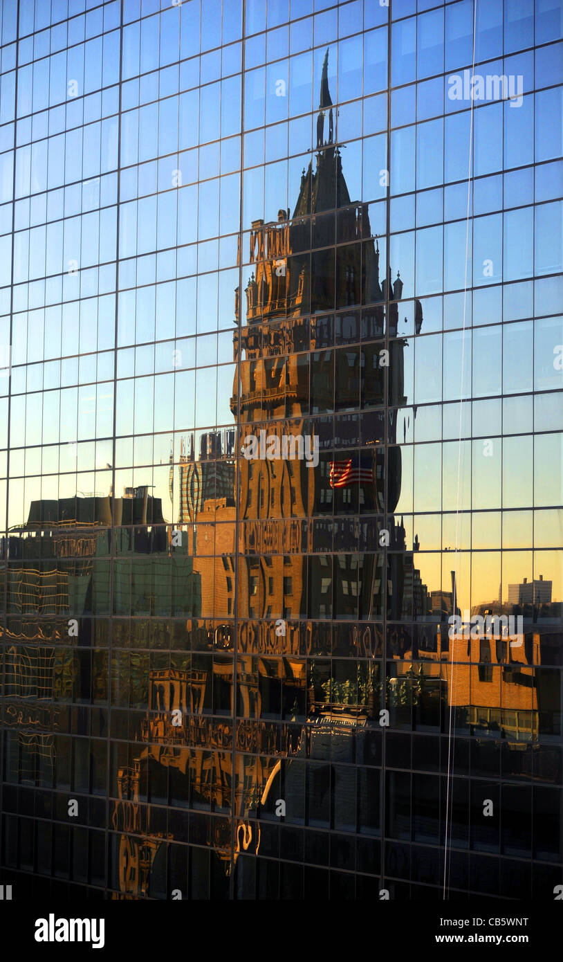 Los rascacielos y la bandera de rayas y estrellas refleja al amanecer en un edificio con fachada de cristal cerca de Central Park de Manhattan, Nueva York Foto de stock