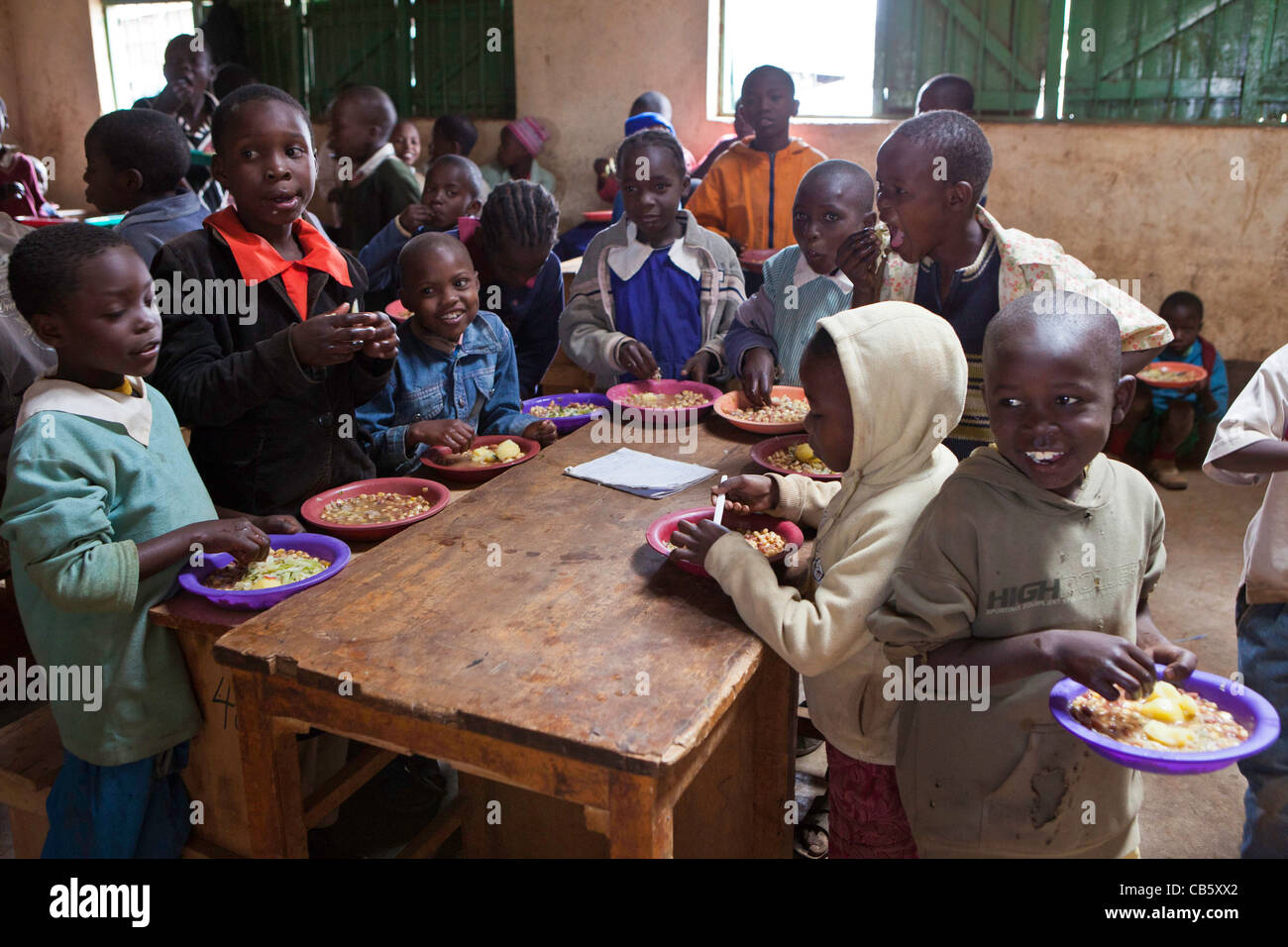 La escuela los niños reciben alimentos recién cocinados en Kibera, Nairobi escuela donde una ONG se ejecuta un programa de alimentación a la hora del almuerzo. Foto de stock