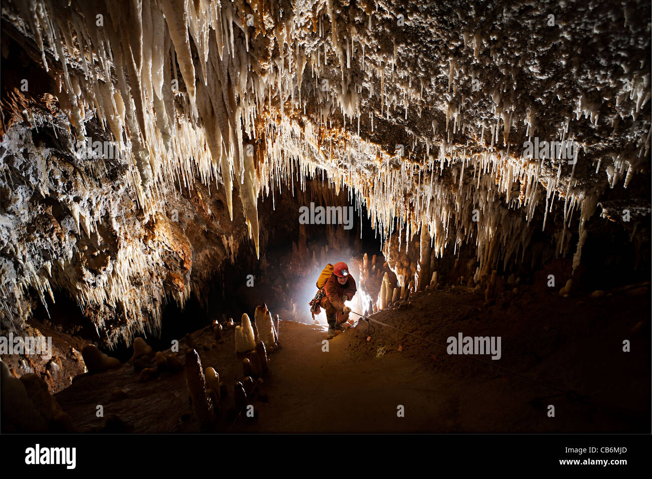 Hembra escalada caver pendiente con estalactitas en la cueva francesa Foto de stock