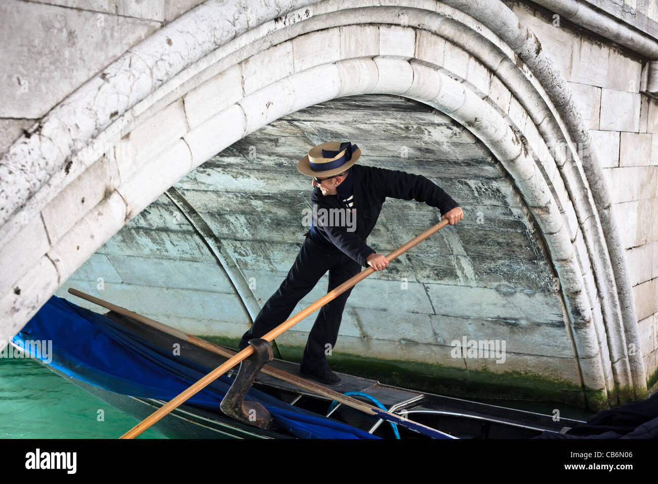 Y su góndola gondolero pasando por debajo de un pequeño puente en Venecia, Véneto, Italia Foto de stock