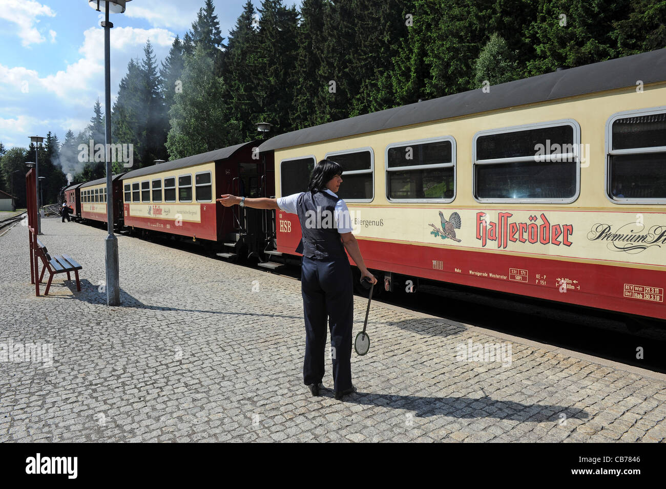 Hembra de guardia de ferrocarril con una locomotora a vapor en Schierke estación de ferrocarril en la región del Harz Alemania Sajonia-Anhalt Foto de stock