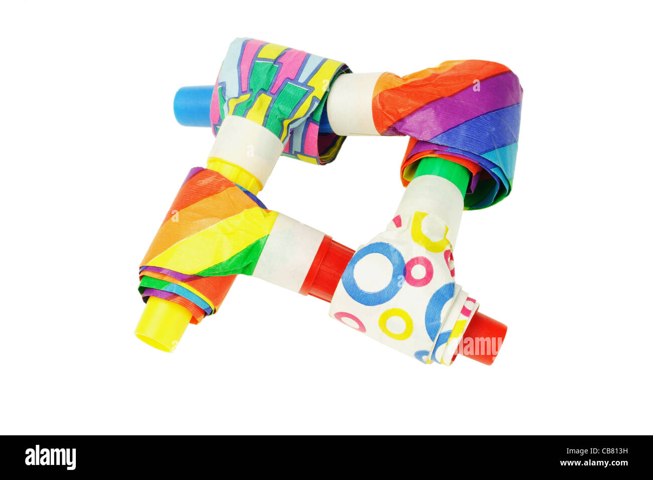 Sopladores de fiesta multicolor entrelazados sobre fondo blanco. Foto de stock