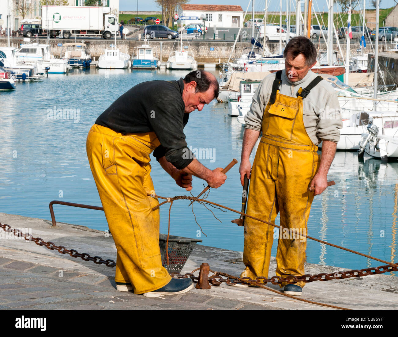 Dos pescadores empalmando cables en el Quayside, St Martin en Re, Ile de Re, Charante-Maritime, Francia Foto de stock