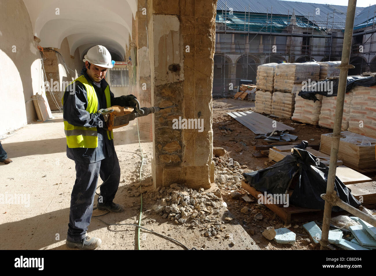 Trabajador de la construcción con un martillo neumático en un sitio en construcción Foto de stock