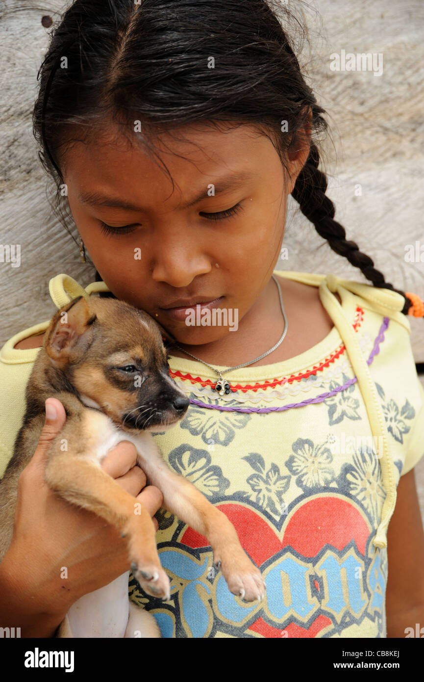 Guna niña india abrazando a un cachorro de perro en la isla Corbisky en Guna Yala, Panamá. Foto de stock