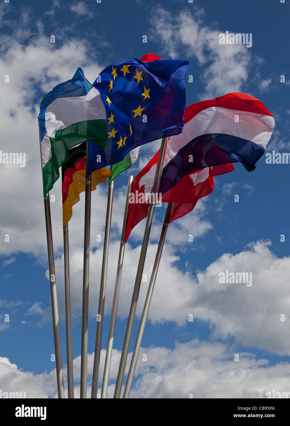 Un grupo de 7 banderas europeas revoloteaban en el viento contra el cielo azul y las nubes Foto de stock