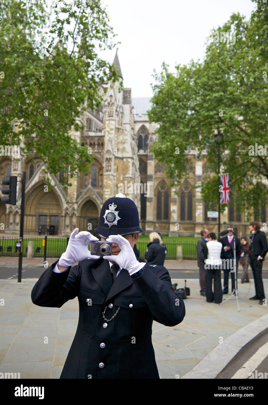 Oficial de policía en la Plaza del Parlamento tomando fotos de multitudes fuera de la Abadía de Westminster durante el matrimonio del Príncipe William Foto de stock