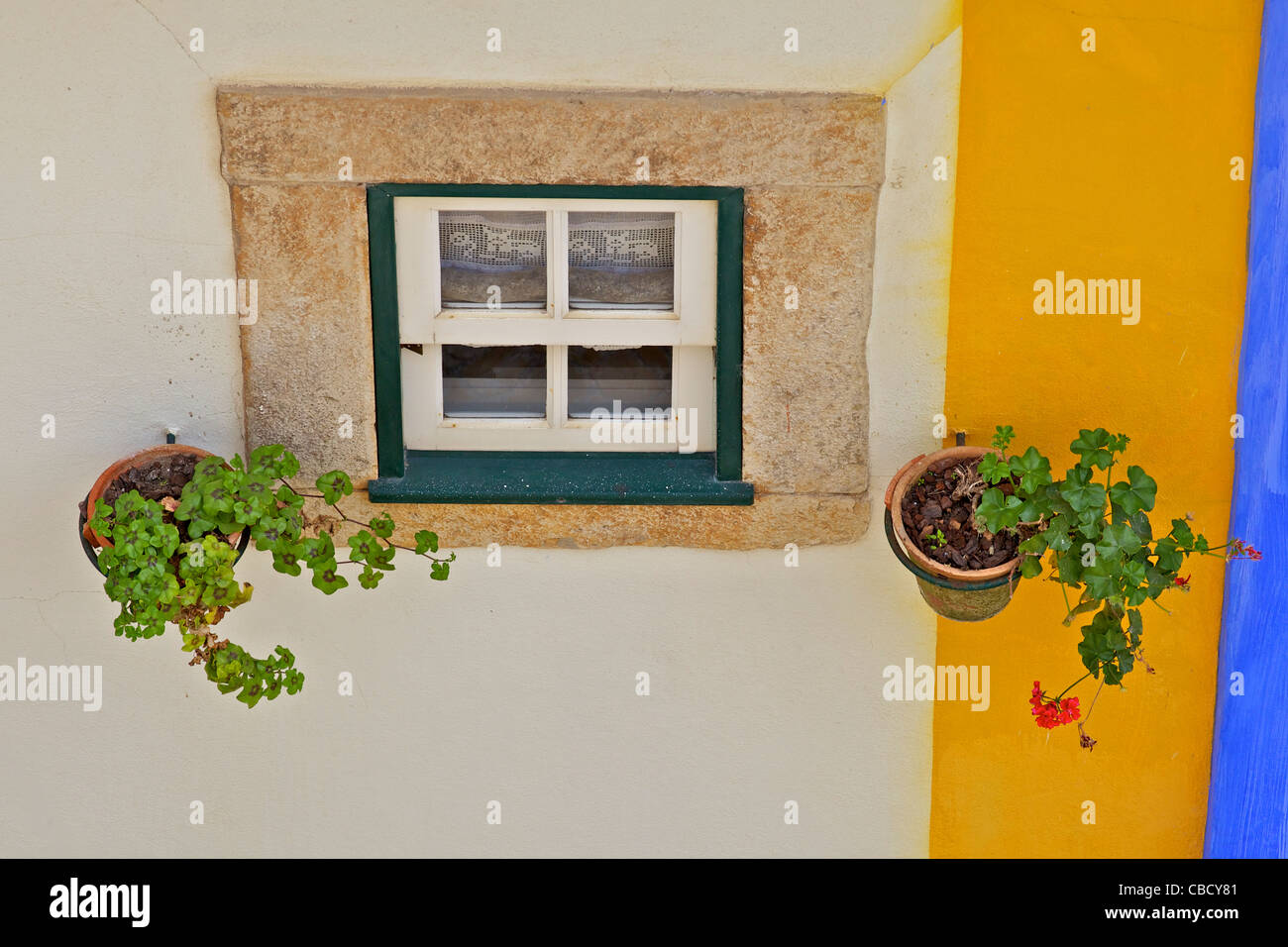 Ventana y techo de tejas de arcilla con una pared de color pastel en el pueblo medieval de Obidos. Foto de stock