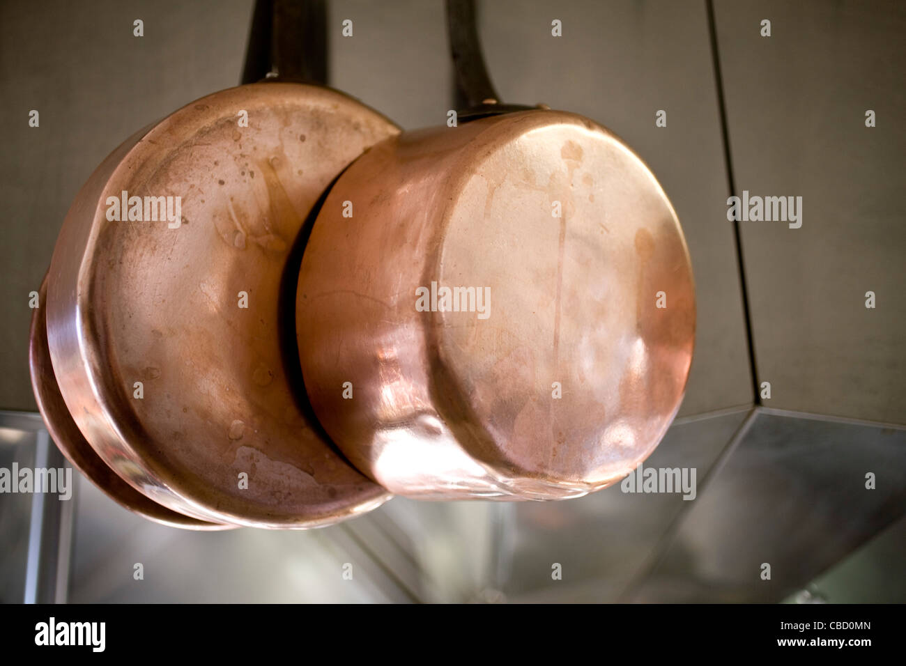 Sartenes de cobre que cuelgan en la cocina Foto de stock