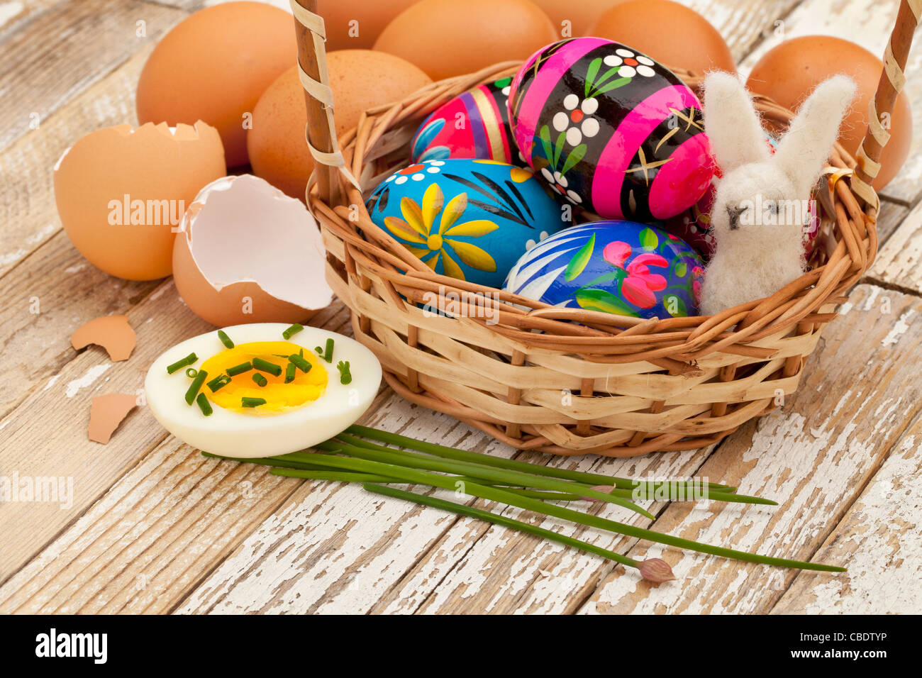 Concepto de decoración de Pascua - Huevos de Pascua pintados, huevos de gallina con cebolleta verde y el conejito de lana en una cesta Foto de stock