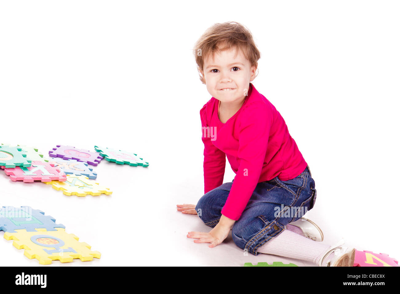 Cute Little Girl resolviendo rompecabezas del alfabeto sobre fondo blanco. Foto de stock