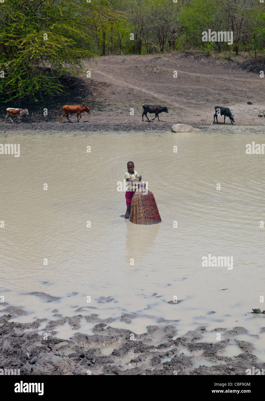 Chica la pesca en el río con una cesta de red para pescar, Angola Foto de stock
