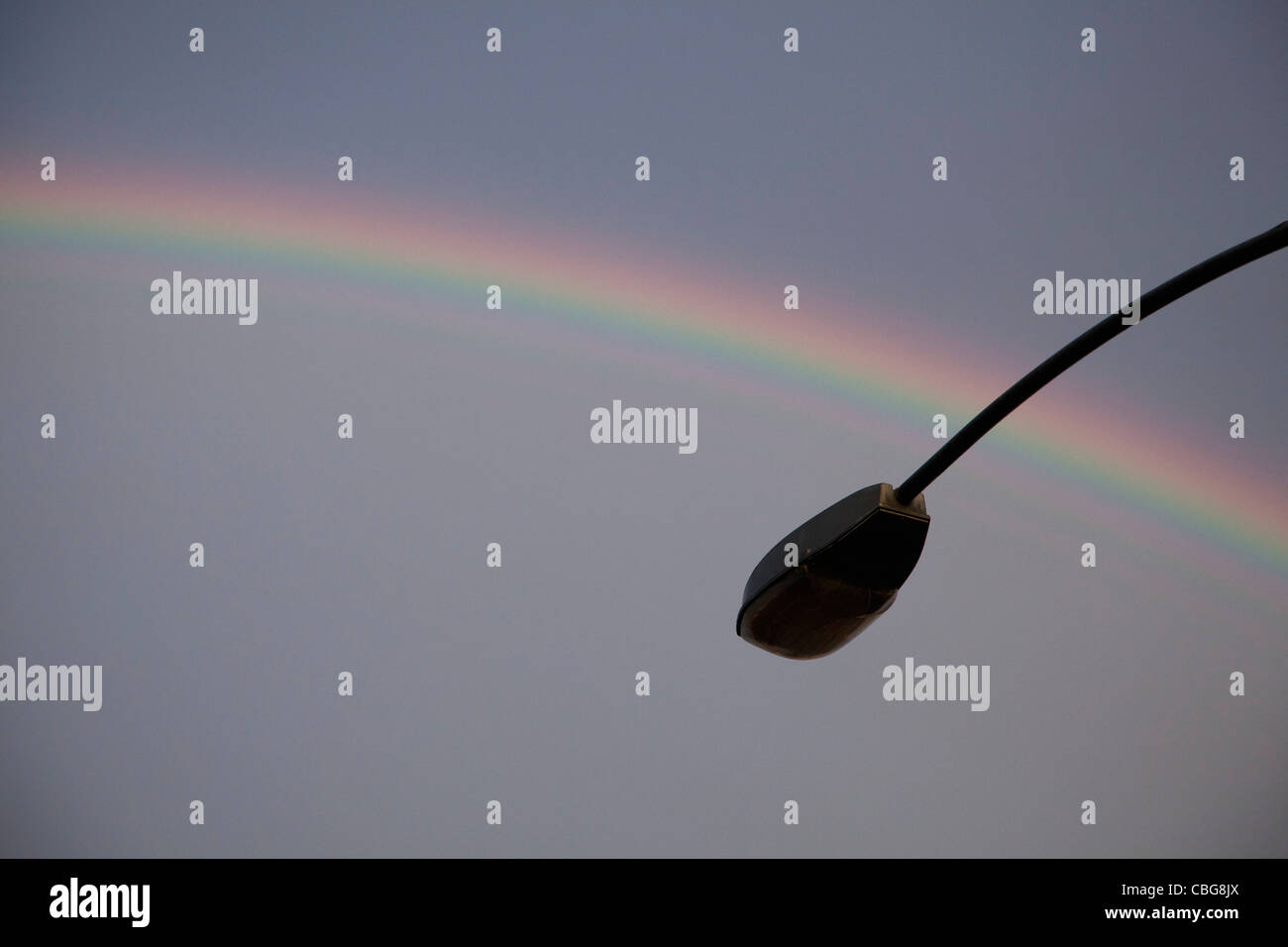 Un arco iris en la parte posterior de una silueta lámpara de la calle Foto de stock