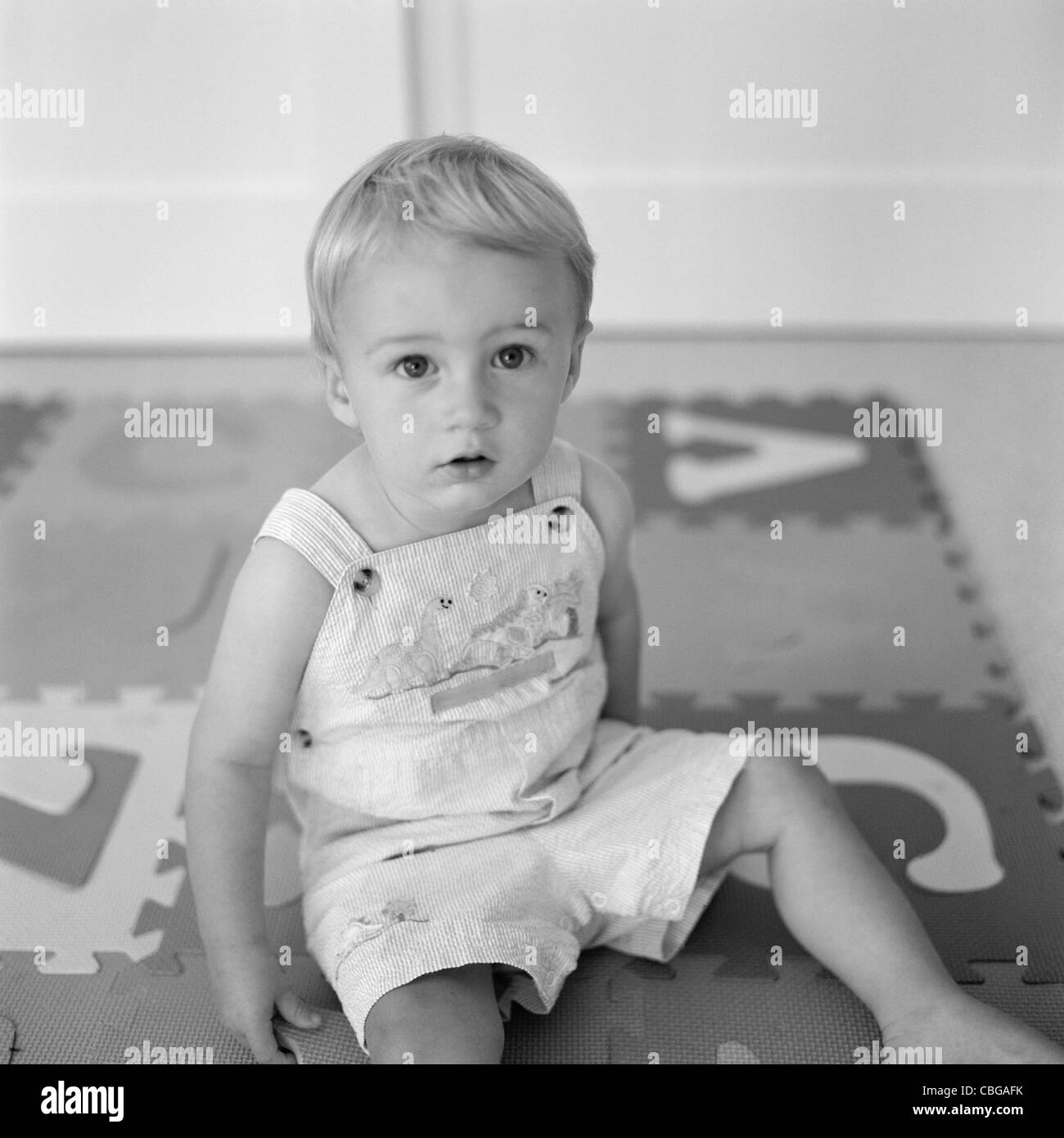 Un niño sentado en un alfabeto rompecabezas mat Foto de stock