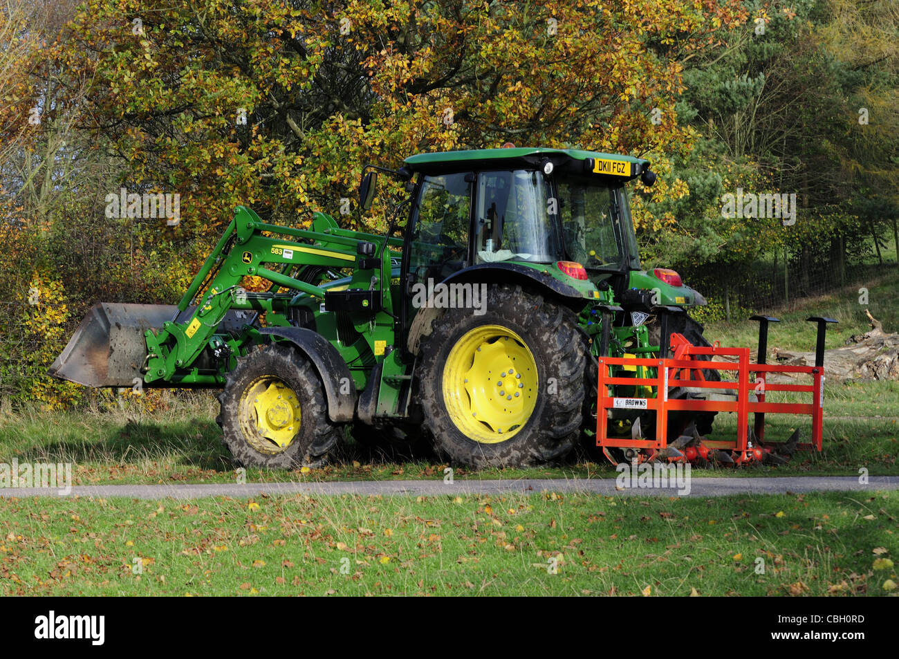 John Deere tractor amarillo y verde con hojas cortantes y la cuchara Foto de stock