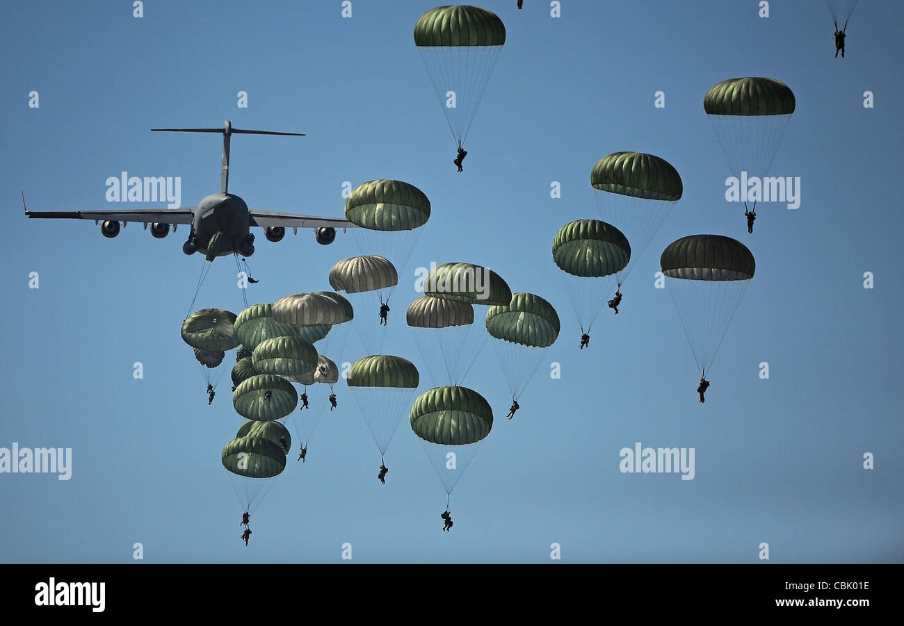 Muchos paracaidistas saltando de un avión con paracaídas depolyed Foto de stock