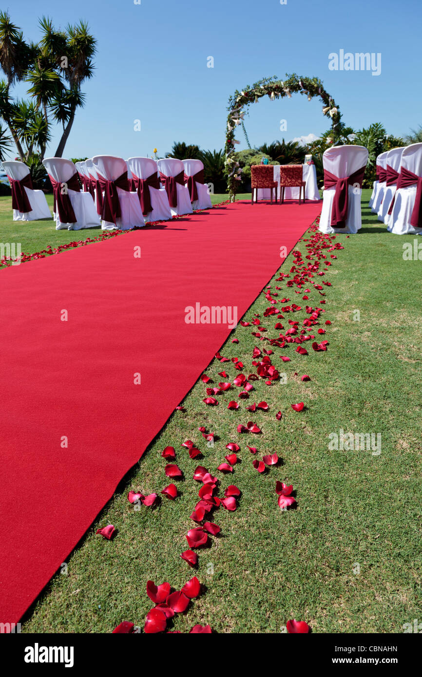 Ajuste de la boda al aire libre con alfombra roja pétalos de flores blanco  cubierto de sillas y un romántico arco Fotografía de stock - Alamy