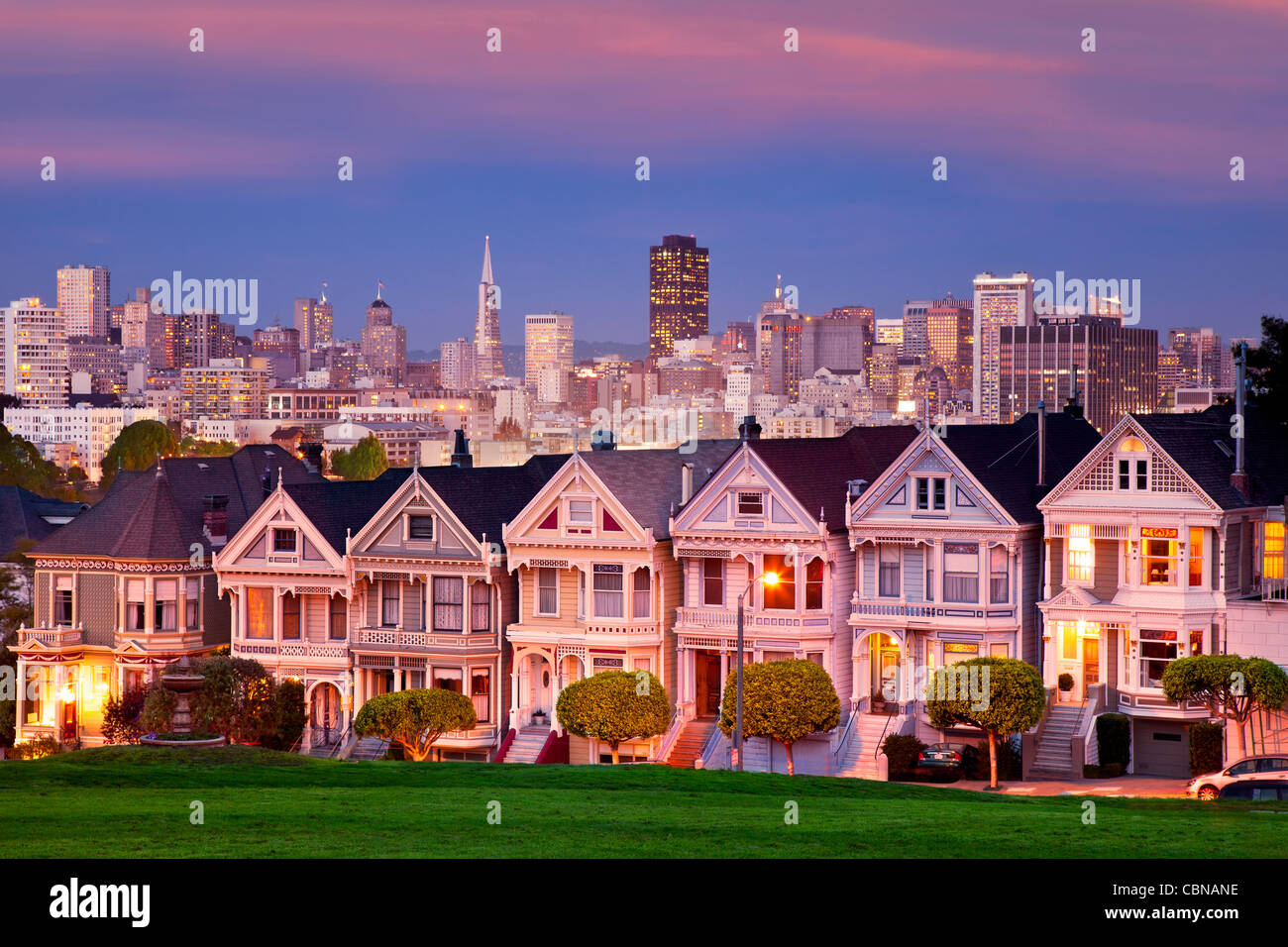 Casas de estilo victoriano - las "Damas Pintadas" de San Francisco con el horizonte más allá de crepúsculo. Foto de stock