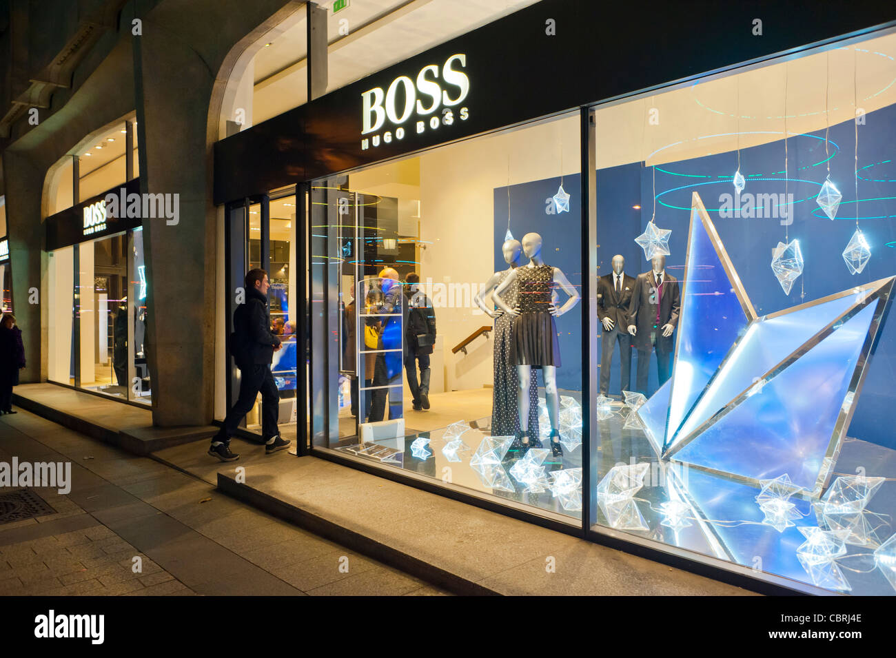 París, Francia, tiendas de ventanas, tienda de ropa de lujo, Boss, Compras  frente al hombre en la noche en la avenida de los Campos Elíseos, ventanas  en la noche Fotografía de stock -