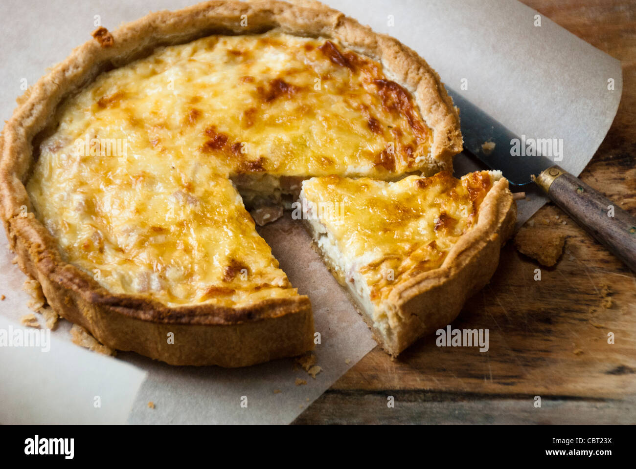 Poco Quiche Lorraine sobre papel absorbente con la cuchilla rizada Foto de stock