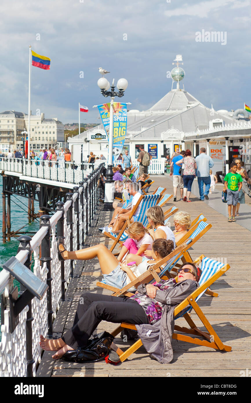 La gente de vacaciones y vacaciones sentarse, relajarse, caminar y disfrutar de ellos en el Brighton Pier Boardwalk. Foto de stock