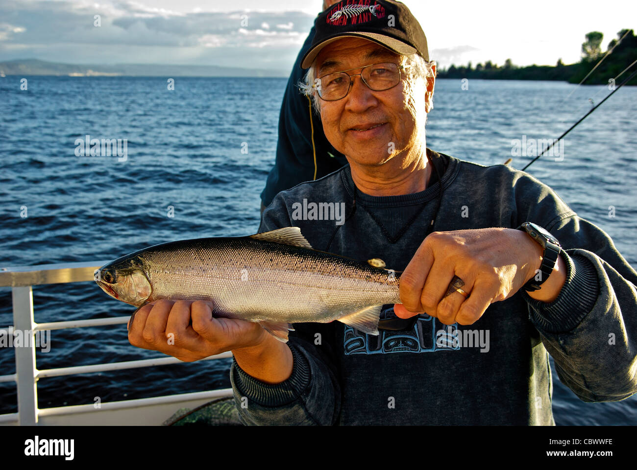 Feliz celebración pescador Masculino Asiático fat Gran Lago Taupo trucha arco iris en sus manos Foto de stock