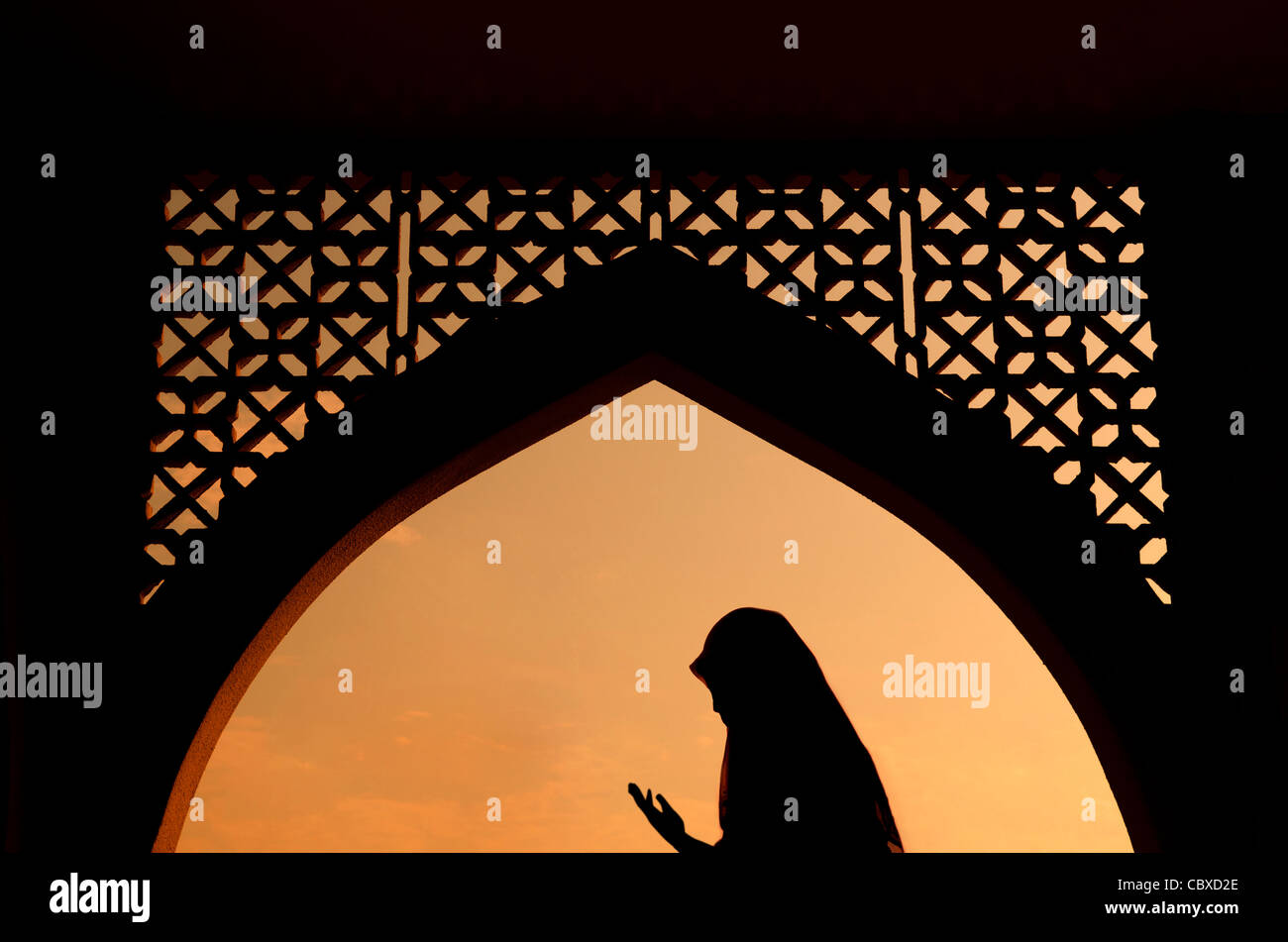 Silhoutte de mujer musulmana rezando durante el sagrado mes de ayuno del ramadán Foto de stock