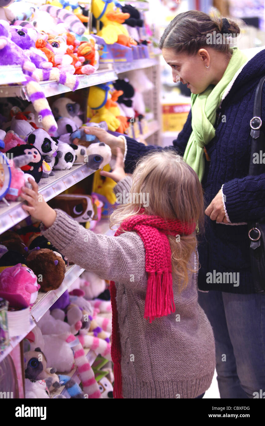 Madre e hija en un departamento de juguetes infantiles, hacer una compra Foto de stock