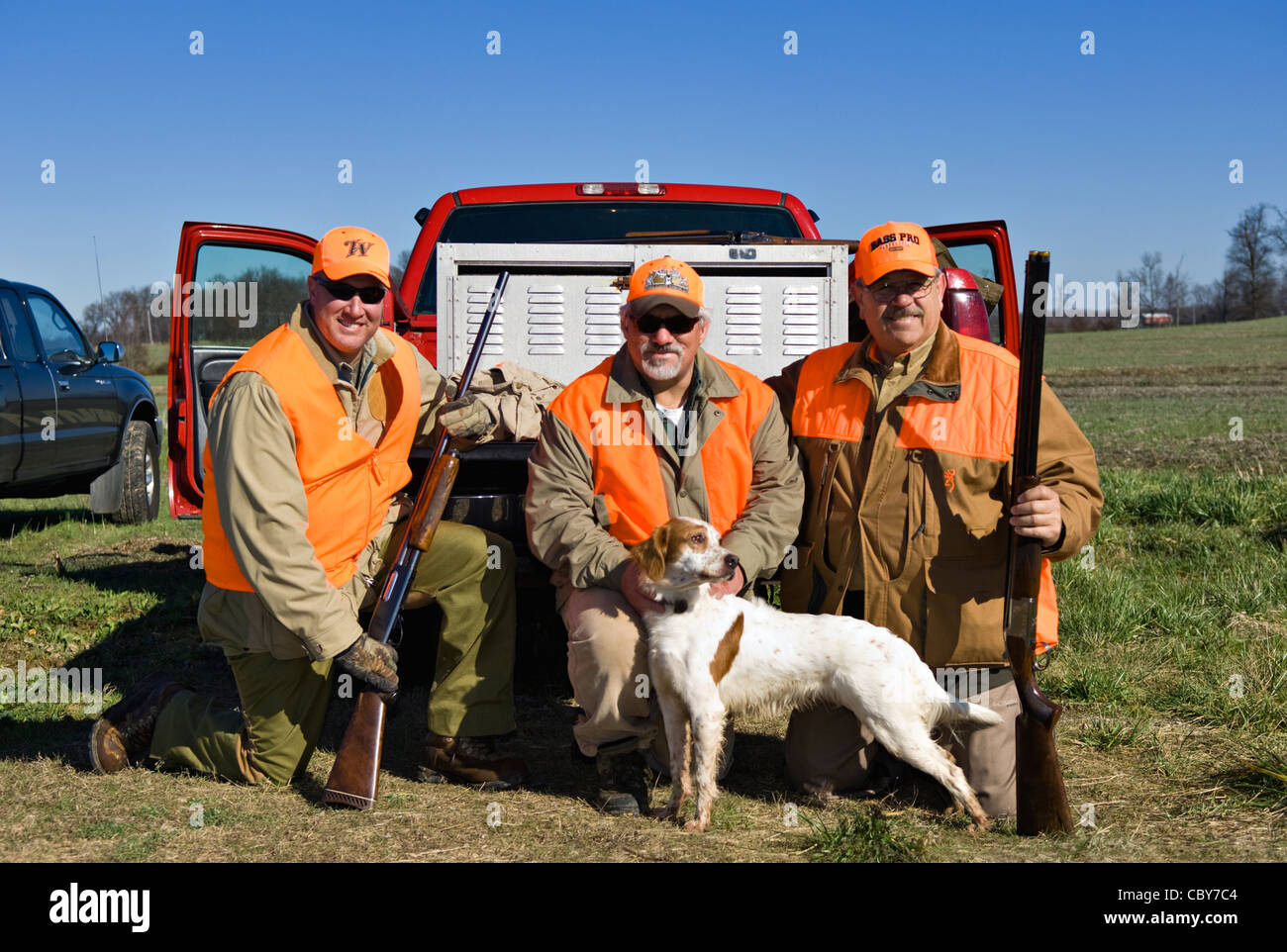 Tres cazadores de aves de montaña posando detrás del camión con escopetas, codornices y Setter inglés Foto de stock