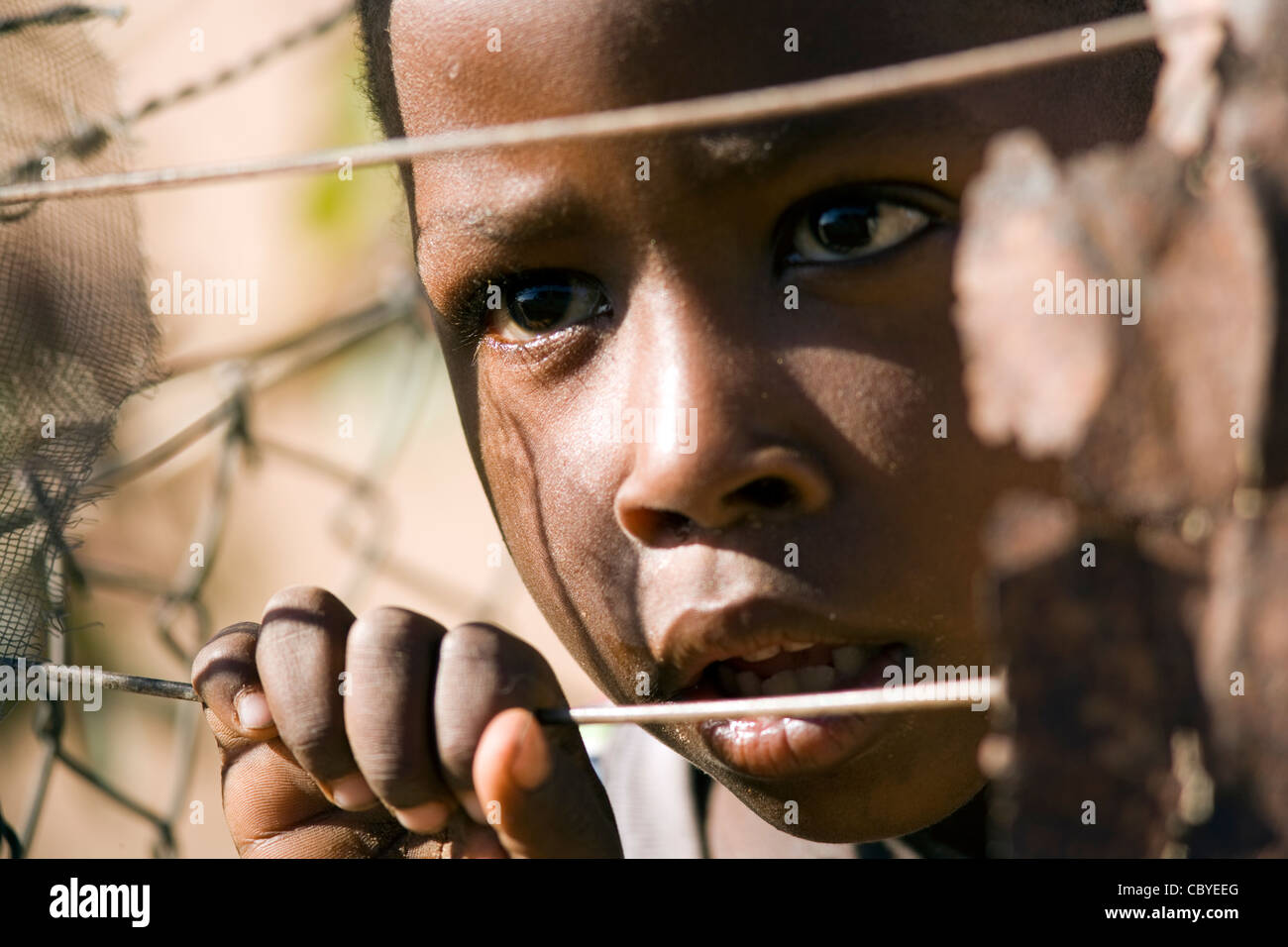 Niño Africano mirando a través de la valla de alambre - Twyfelfontein - Damaraland, Namibia, África Foto de stock