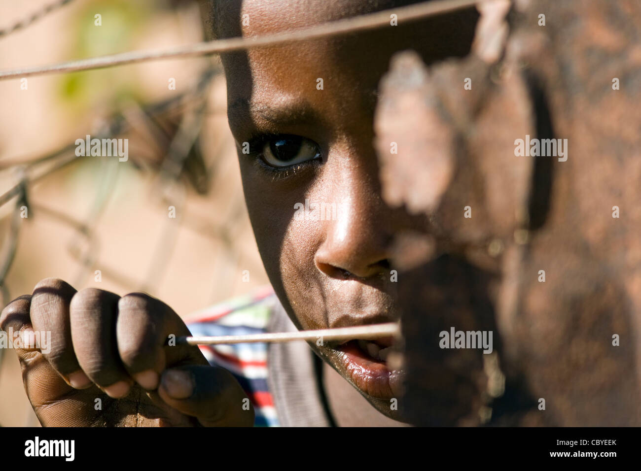 Niño Africano mirando a través de la valla de alambre - Twyfelfontein - Damaraland, Namibia, África Foto de stock