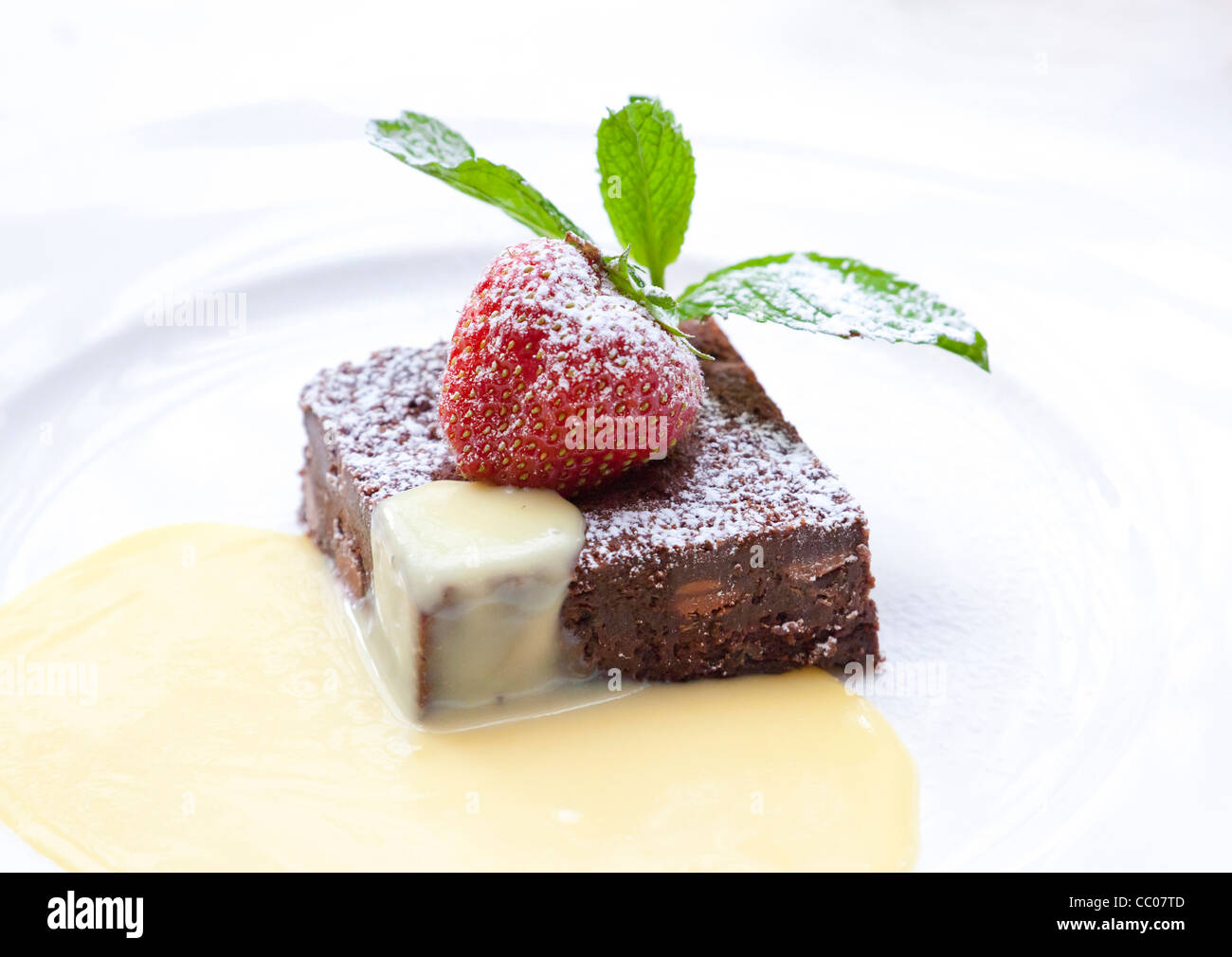 Brownie de chocolate con fresa cortes y servido con natillas Foto de stock