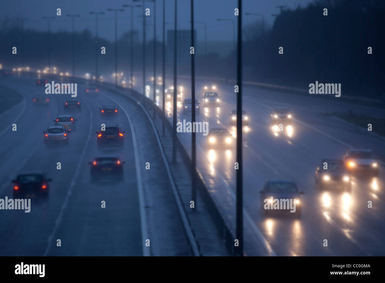 Los coches y el tráfico en un húmedo lloviendo tarde en uk autopista, conducción peligrosa en condiciones invernales. Foto de stock
