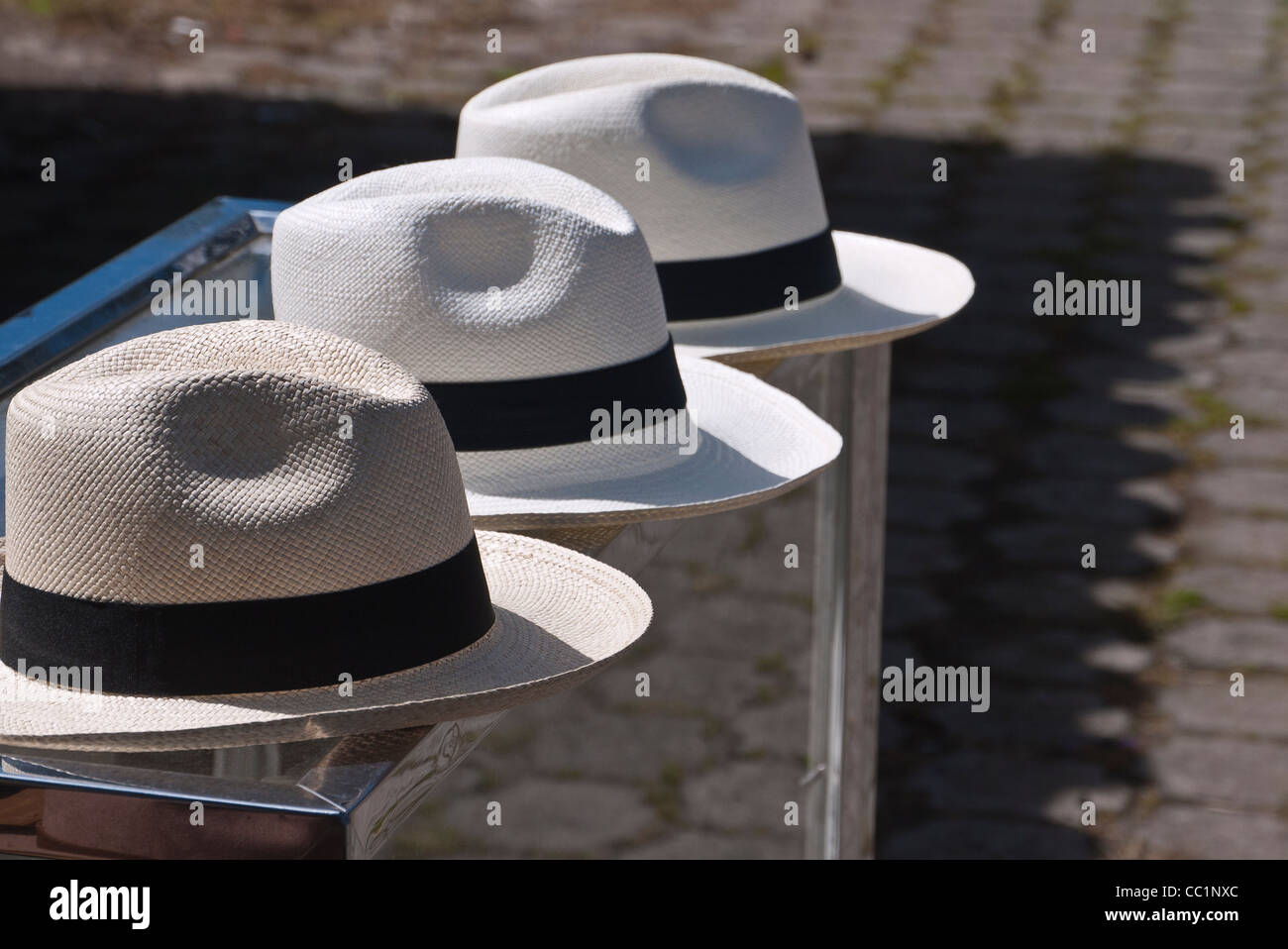 Tres sombreros de Panamá sentado sobre un contador con un patrón en el terreno de la sombra de un techo de tejas creando una fuerte gráfico. Foto de stock