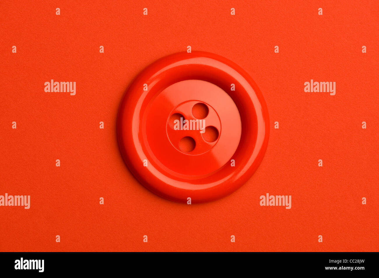 Un botón rojo sobre un fondo rojo. Foto de stock