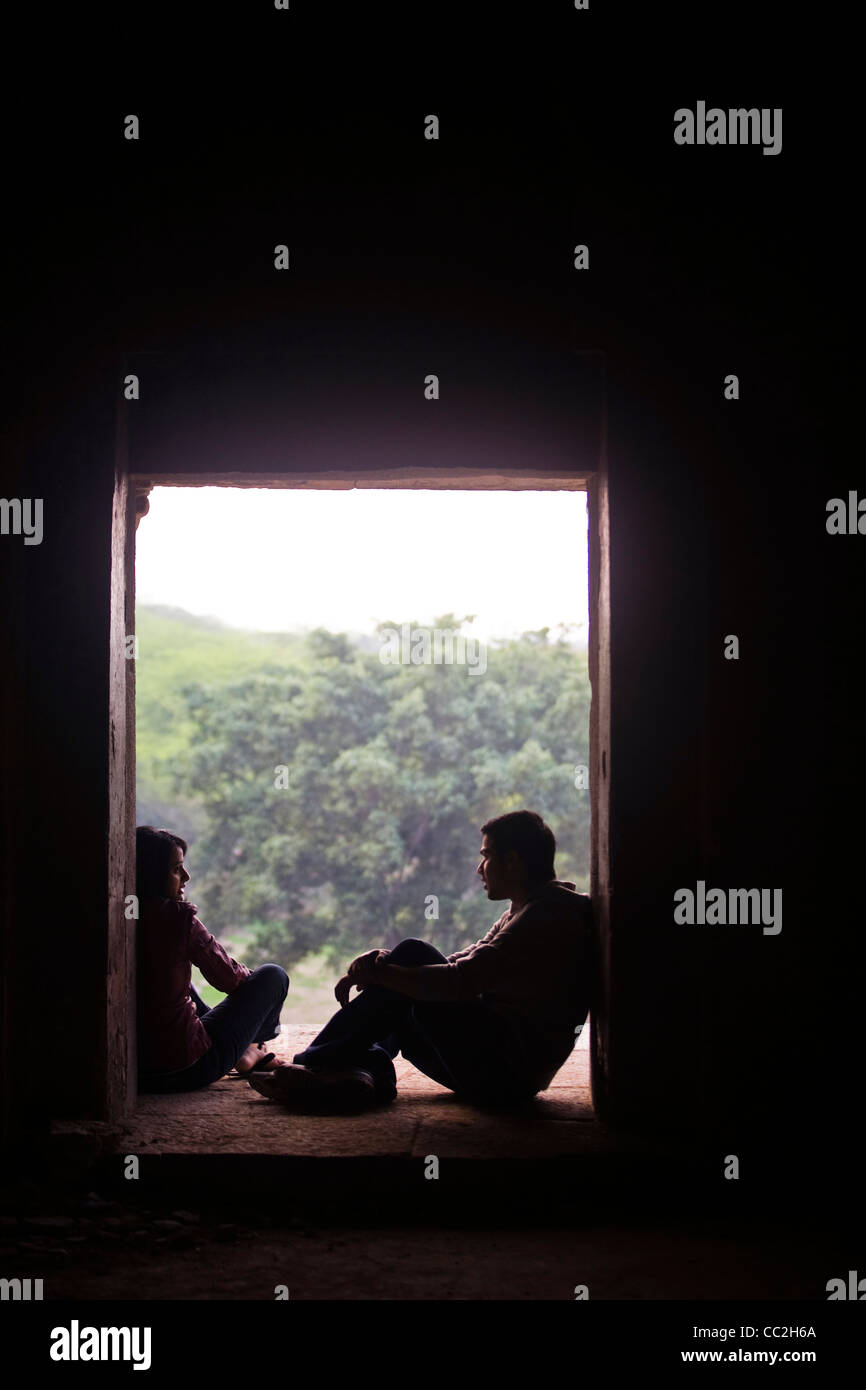 Una joven pareja romántica sentarse en una ventana de las ruinas de una madrassa Hauz Khas, Nueva Delhi, India Foto de stock