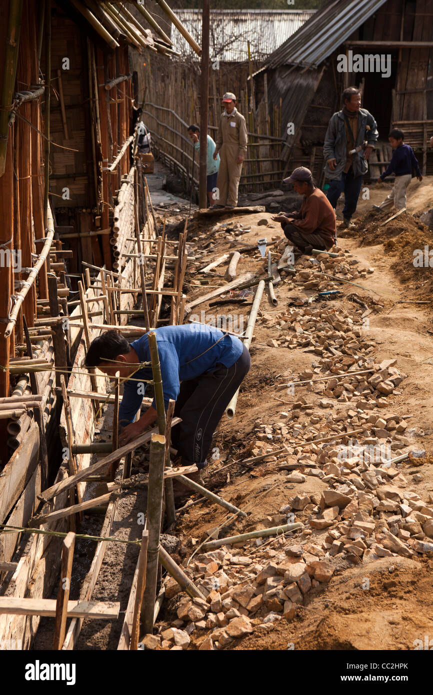 La India, Arunachal Pradesh, antiguos miembros de la comunidad de aldea Ziro reparación de drenaje en el borde de la calle principal Foto de stock