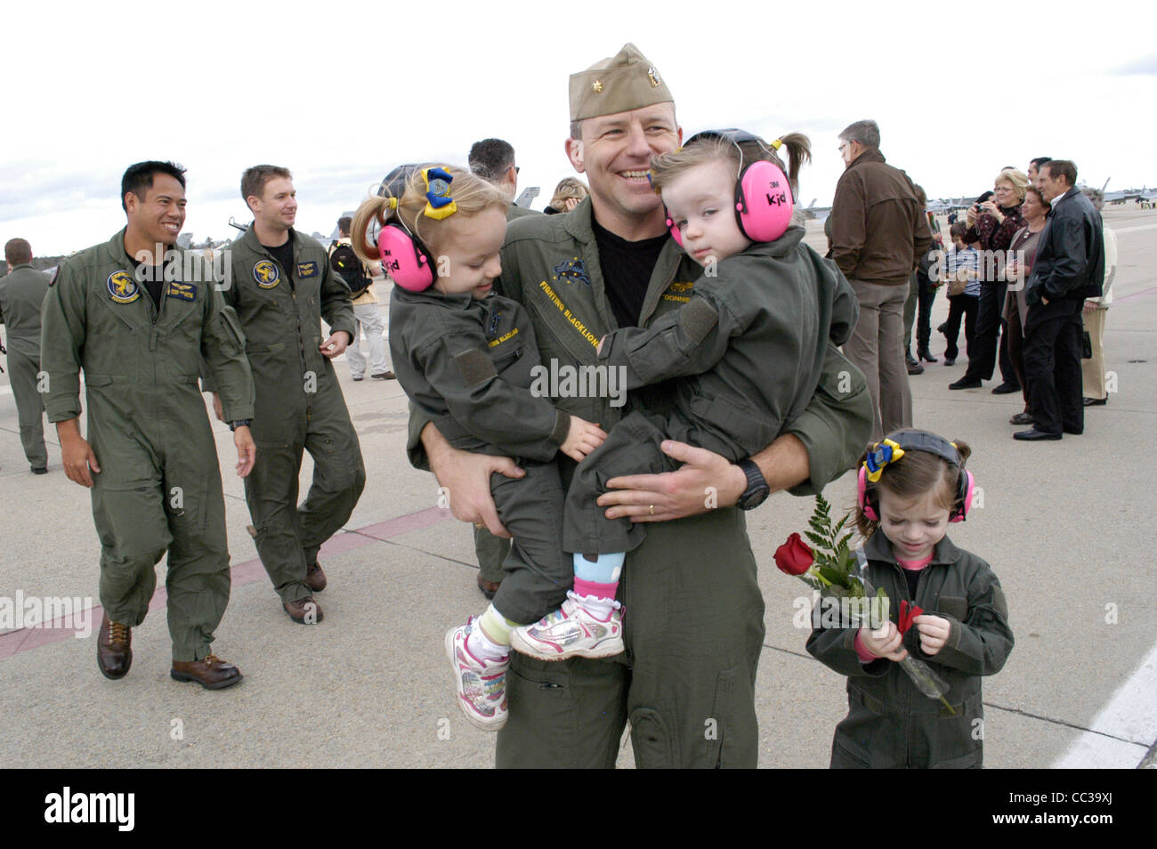 Joseph Greenslade, asignado al Strike Fighter Squadron (VFA) 213, se abraza a sus dos hijas gemelas después de seis meses de implementación. Foto de stock