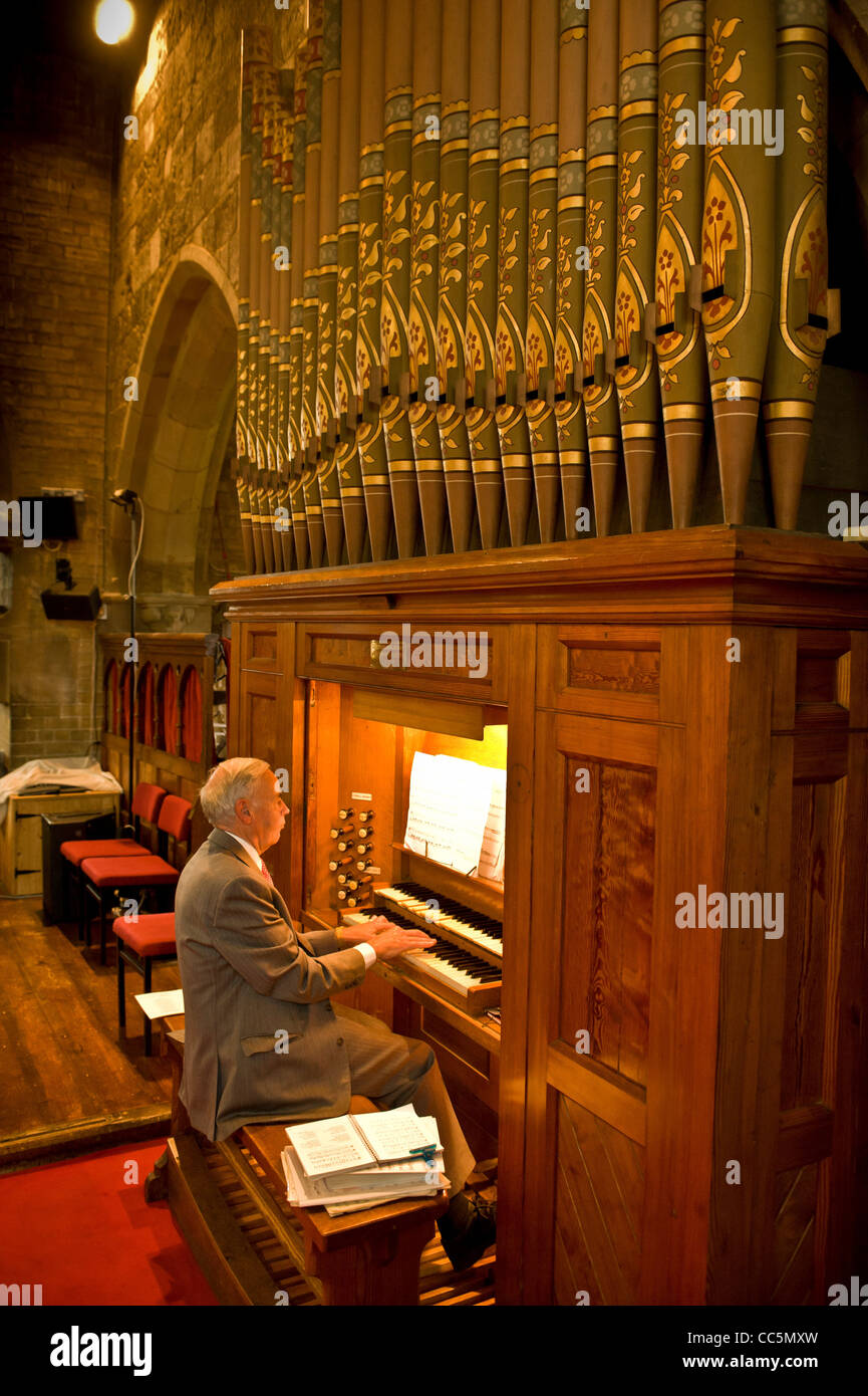 Varón caucásico mayor tocando el órgano en una iglesia del Reino Unido. Foto de stock