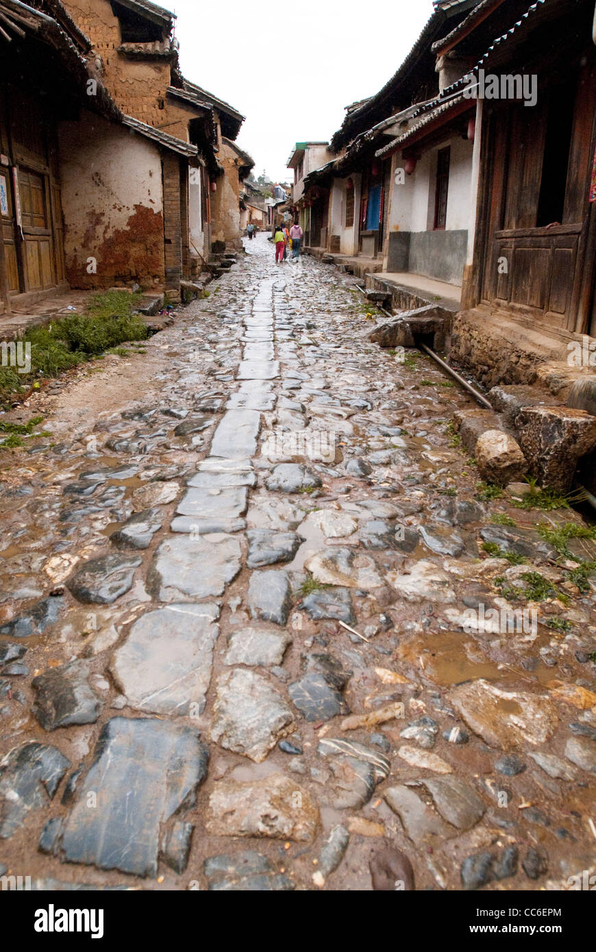 Camino pavimentado de piedra entre casas tradicionales, antiguo pueblo Yi de Yunnan, Xiangyun, Dali, Yunnan, China Foto de stock