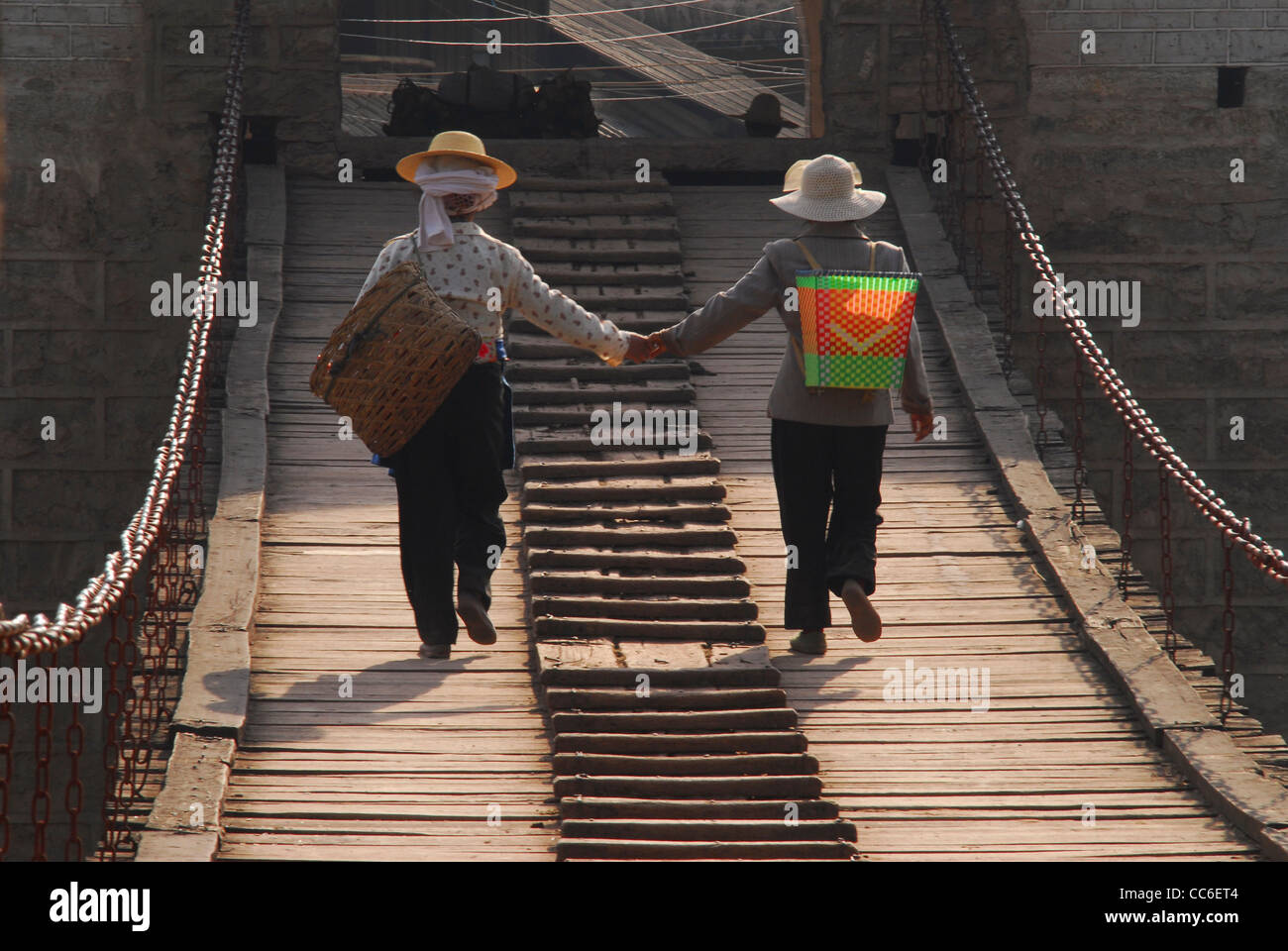 Yi mujeres caminando sobre el puente de Yunlong mano a mano, Yangbi, Dali, Yunnan, China Foto de stock