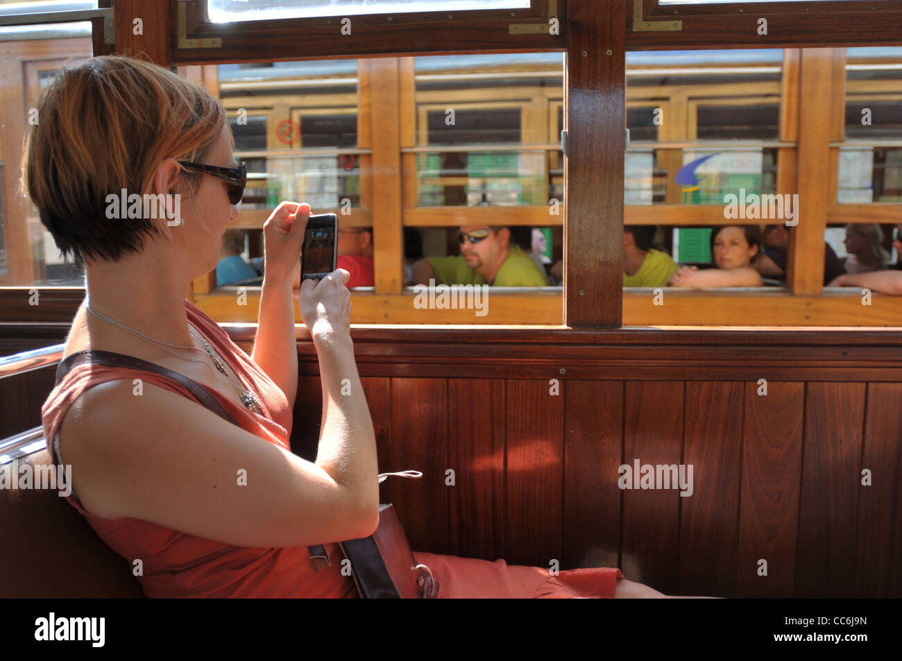 Un turista en un tren en Mallorca tomando fotos con su teléfono inteligente. Foto de stock